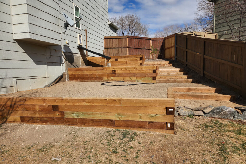Backyard landscaping with wooden steps and retaining walls