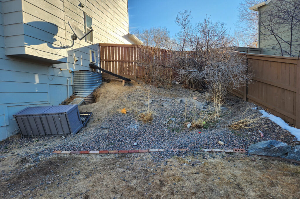 Side yard with gravel and sparse vegetation